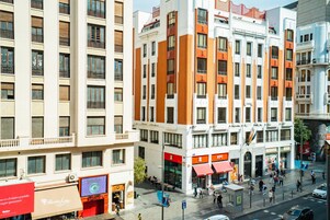 Un hotel a più piani con balconi, un cortile centrale e diversi negozi al piano terra.
