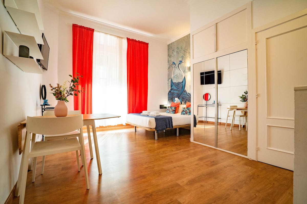 Ein modernes Zimmer mit einem Bett, einem Schreibtisch und einem Essbereich.