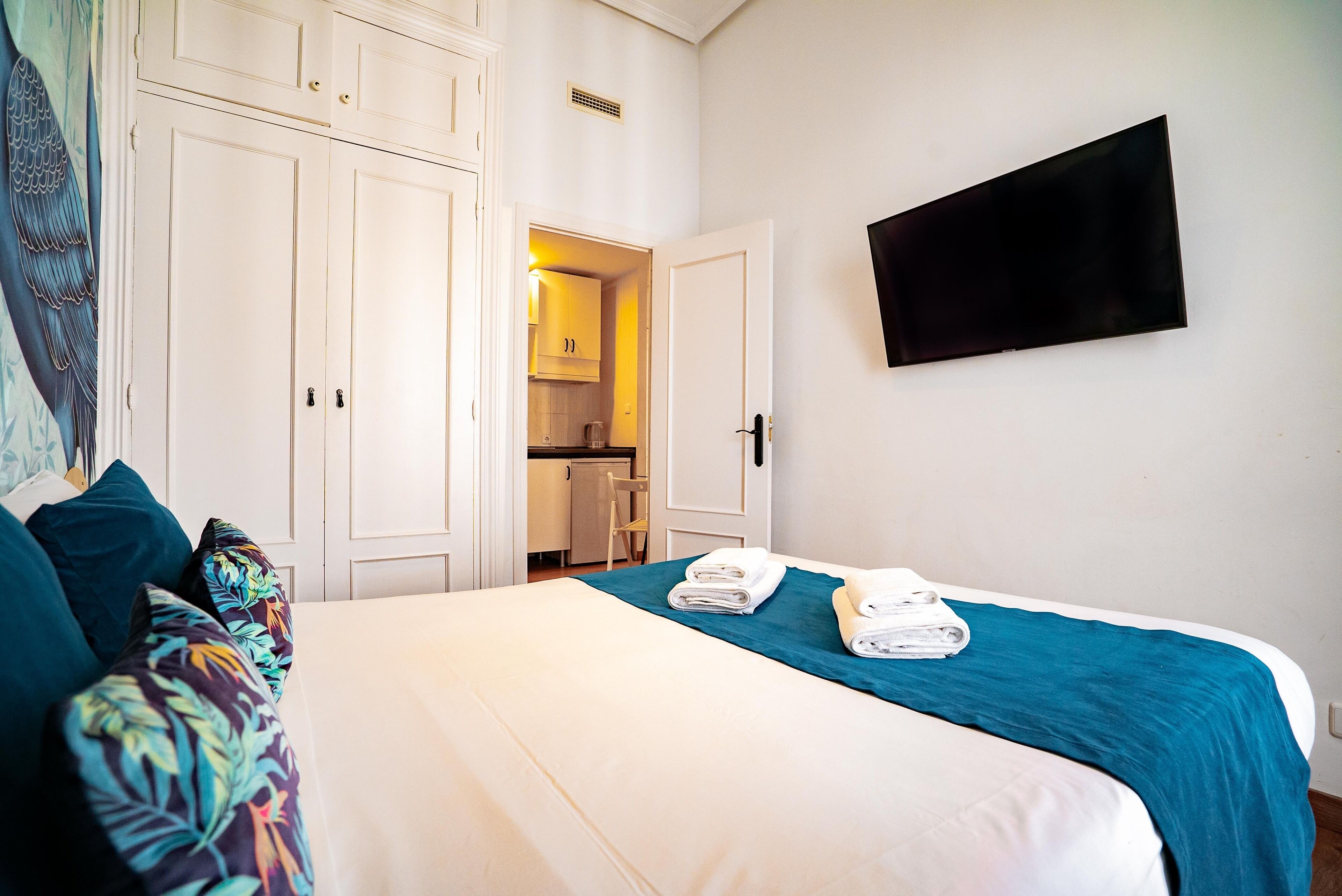 Ein Hotelzimmer mit einem Bett, einem an der Wand befestigten Fernseher und einer Tür zu einem Badezimmer.
