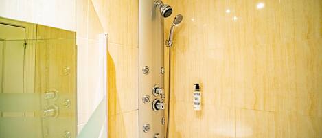Une salle de bain moderne dotée d’une douche à parois de verre, d’un pommeau de douche à main et d’un panneau de commande fixé au mur.