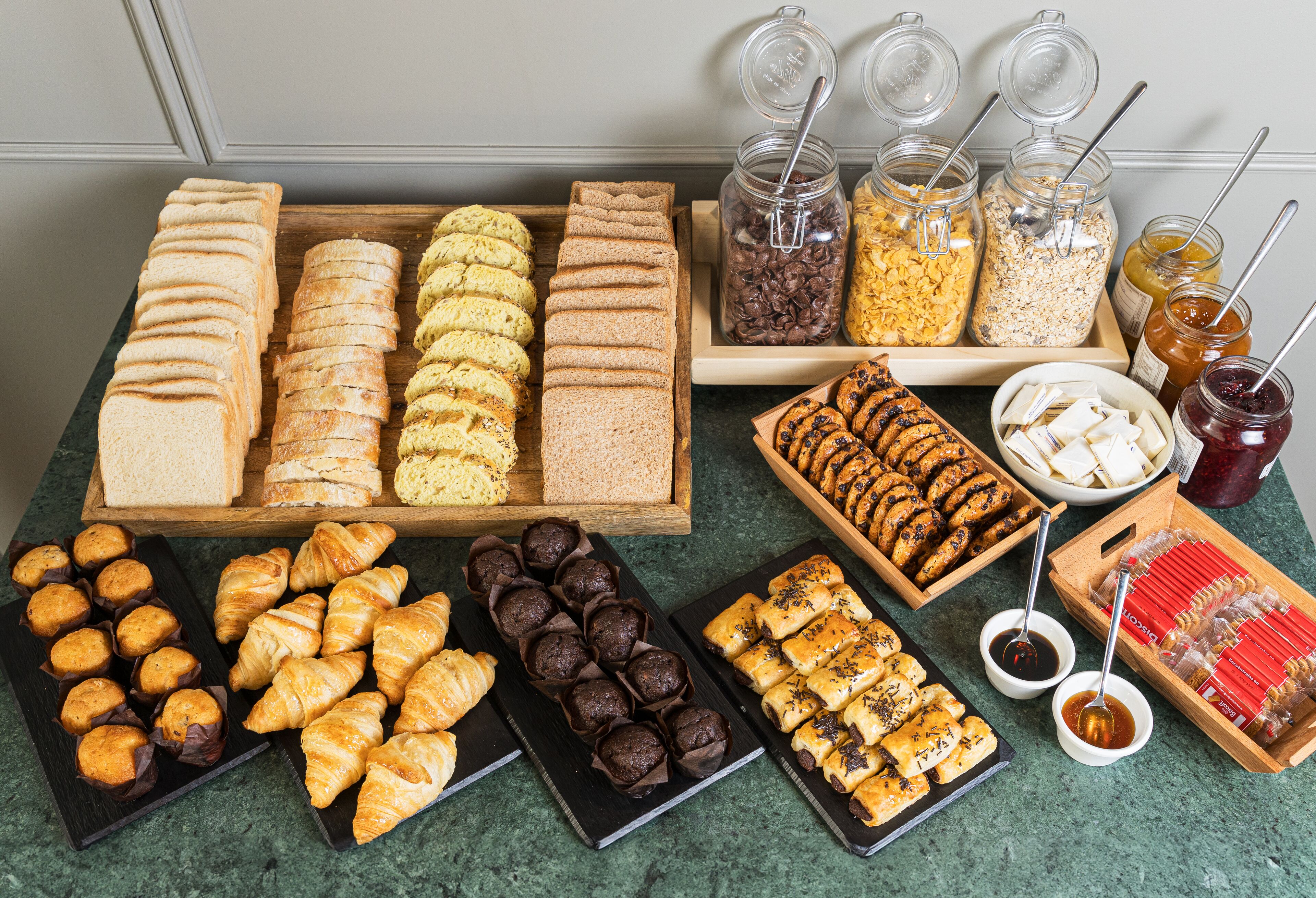 Une grande variété de viennoiseries et de pains sont exposés, notamment des croissants, des muffins et des sandwichs.