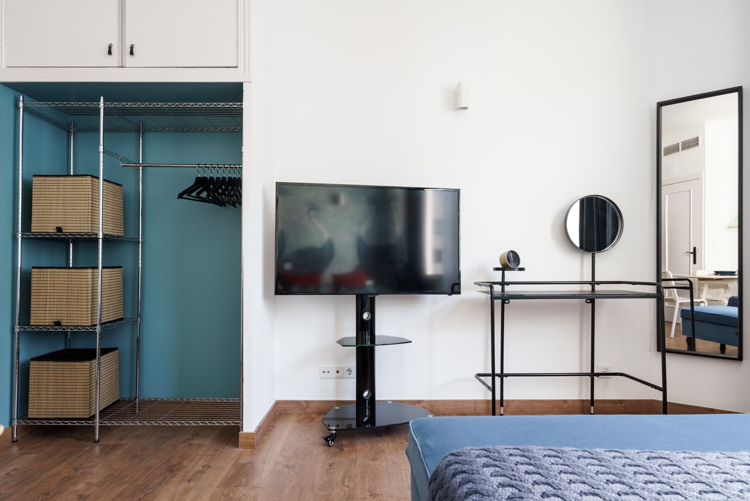 A bedroom with a bed, a TV, a wardrobe, and a mirror.