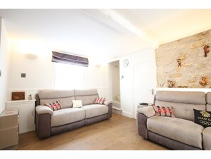 A living room with two sofas, a stone wall, and a small table. - Modern, Chic 3BR Townhouse in Central Oxford (Oxford)
