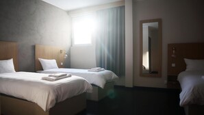 Habitación de hotel con dos camas, un espejo grande y una ventana con cortinas.