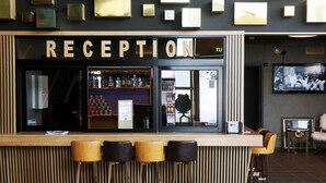Un área de recepción con mostrador de madera, taburetes de bar y una pantalla de televisión.
