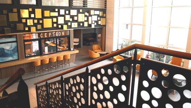 Un área de bar moderna con mostrador de recepción, asientos y ventanas amplias.