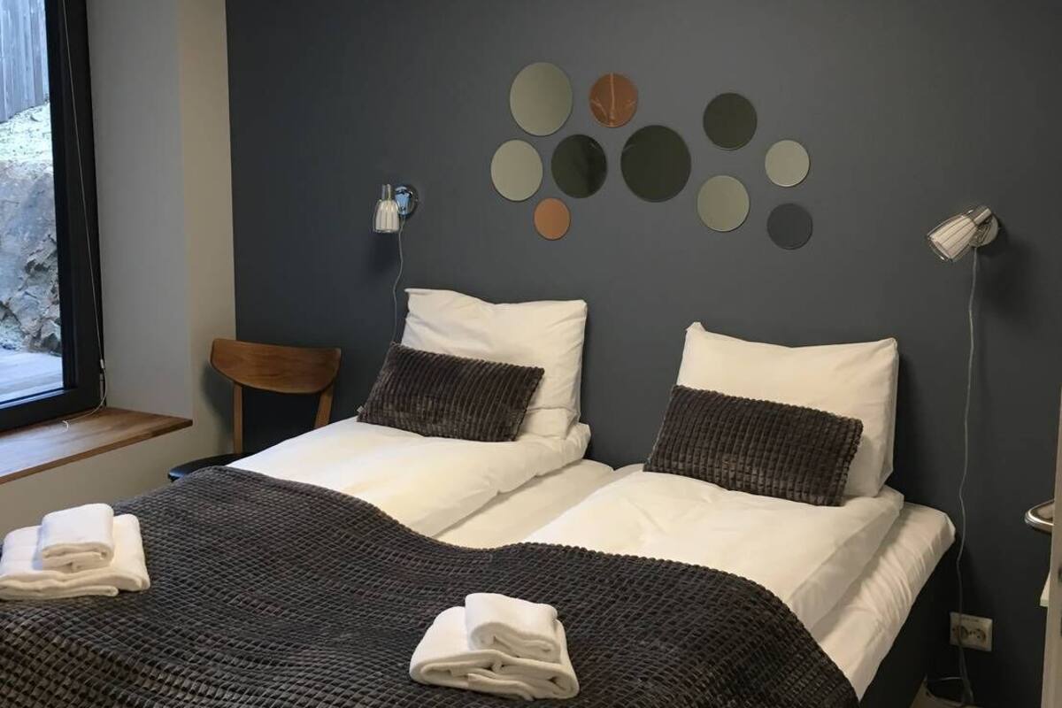 A hotel room with a bed, a chair, a window, and a wall with circular decorations.