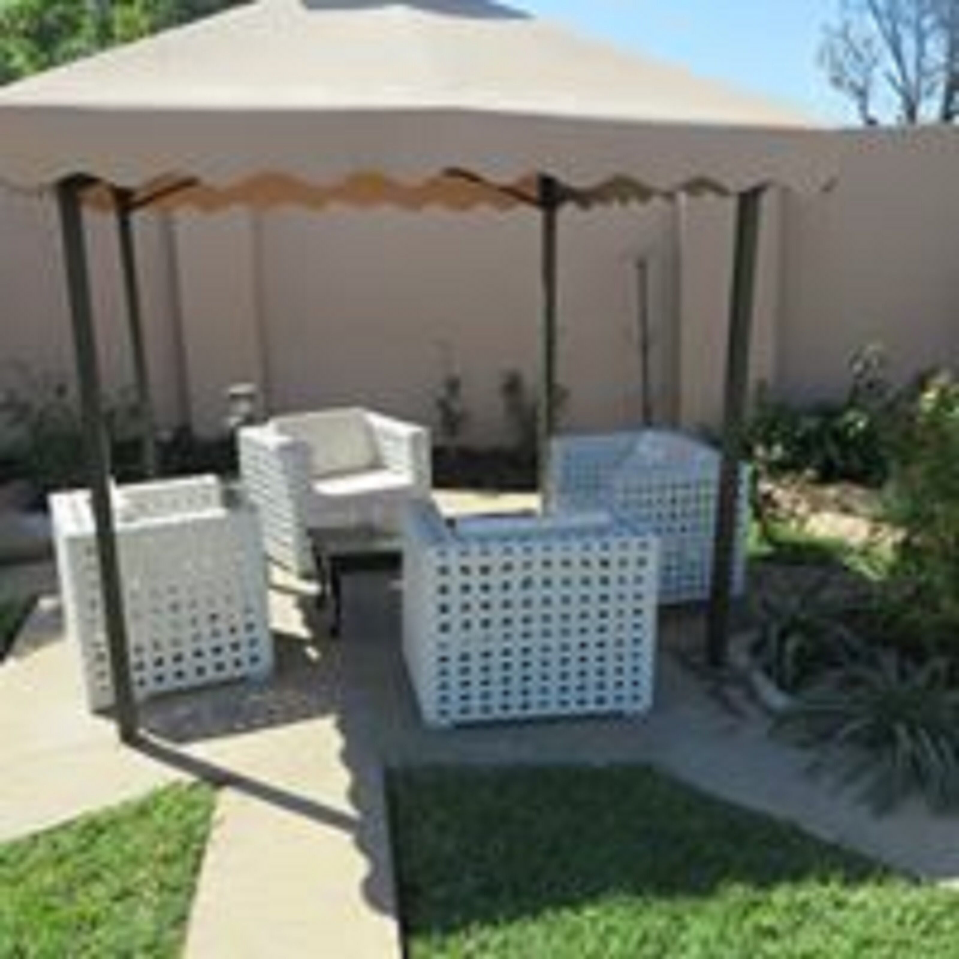 An outdoor patio area with white wicker furniture and a pergola.