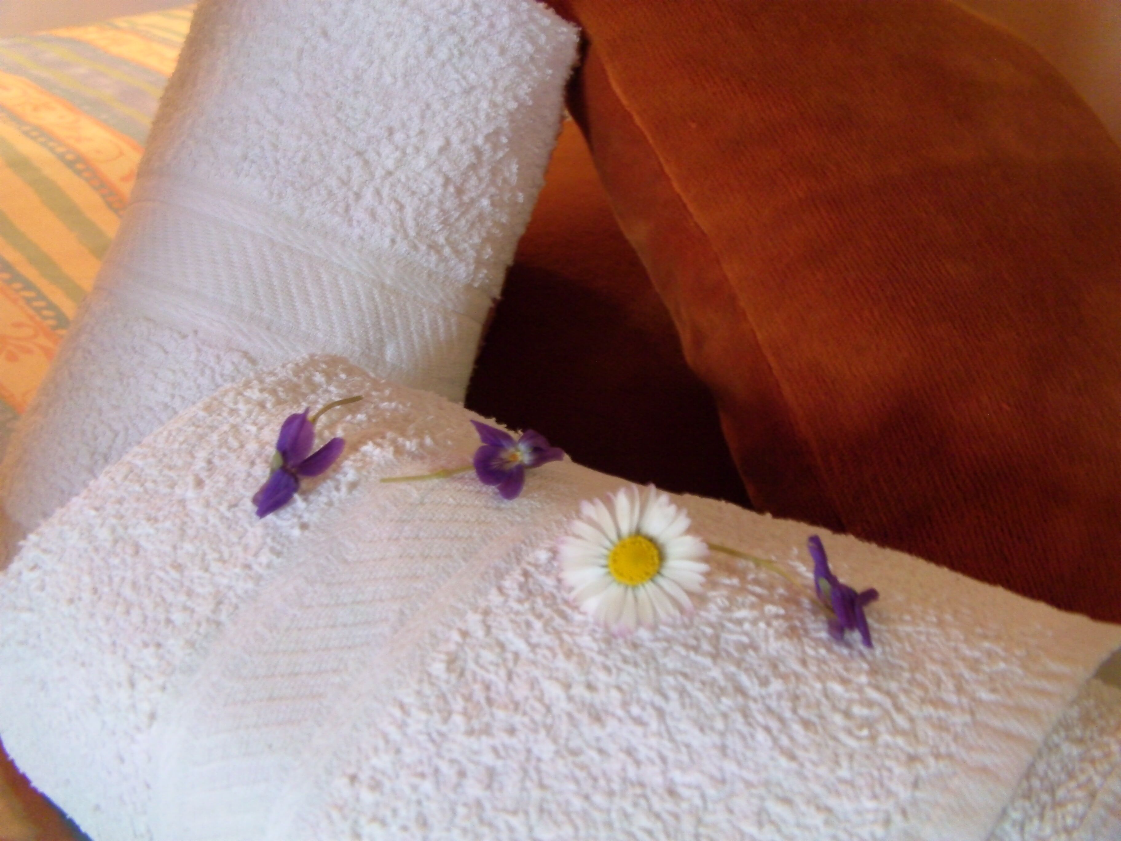 Un asciugamano bianco con fiori viola e una margherita bianca.