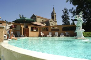 Una piscina con sillas de descanso y una estatua.