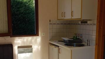 Una cocina compacta con ventana, un refrigerador empotrado y un lavamanos.