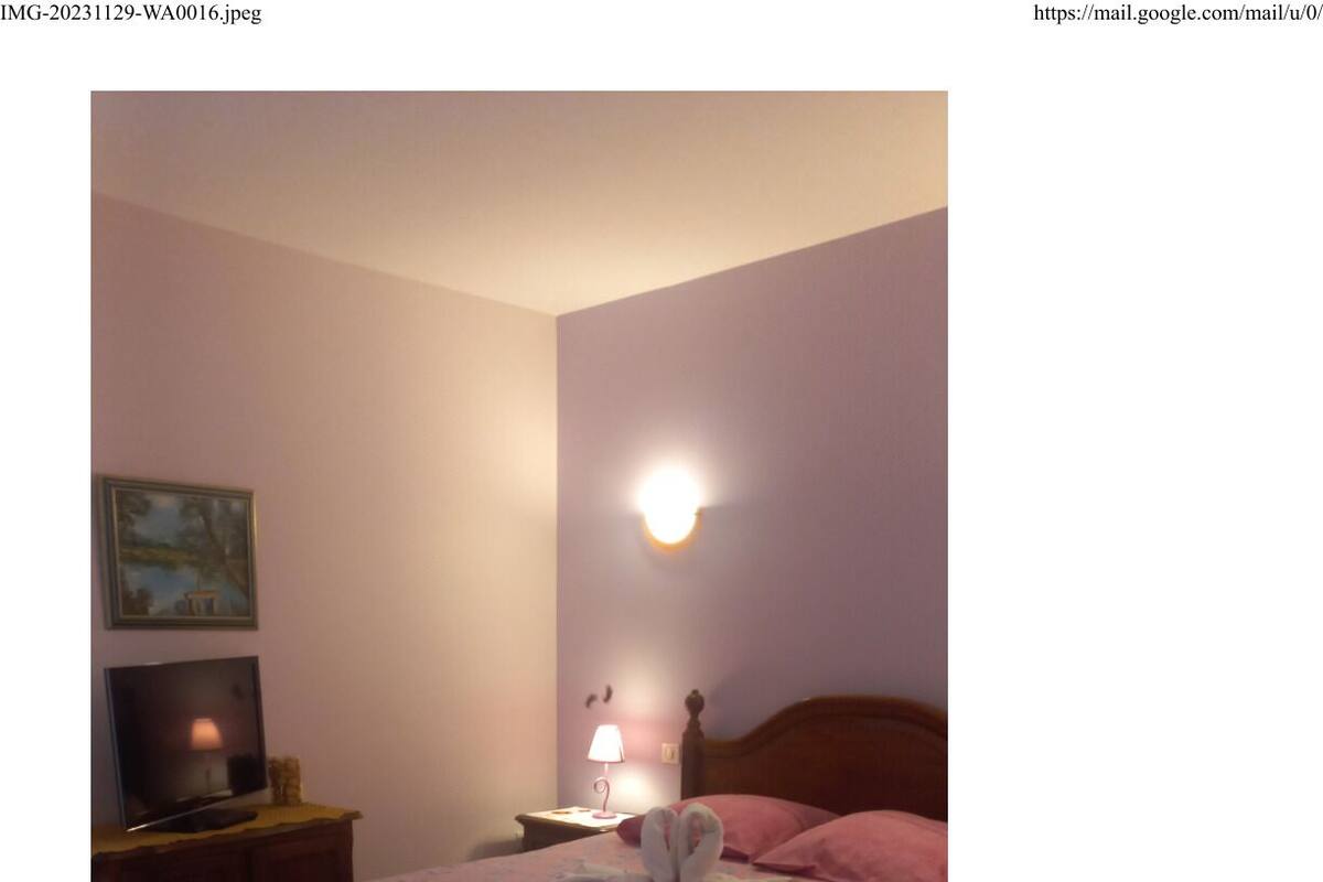 A bedroom with a bed, a nightstand, a lamp, a television, and a painting on the wall.