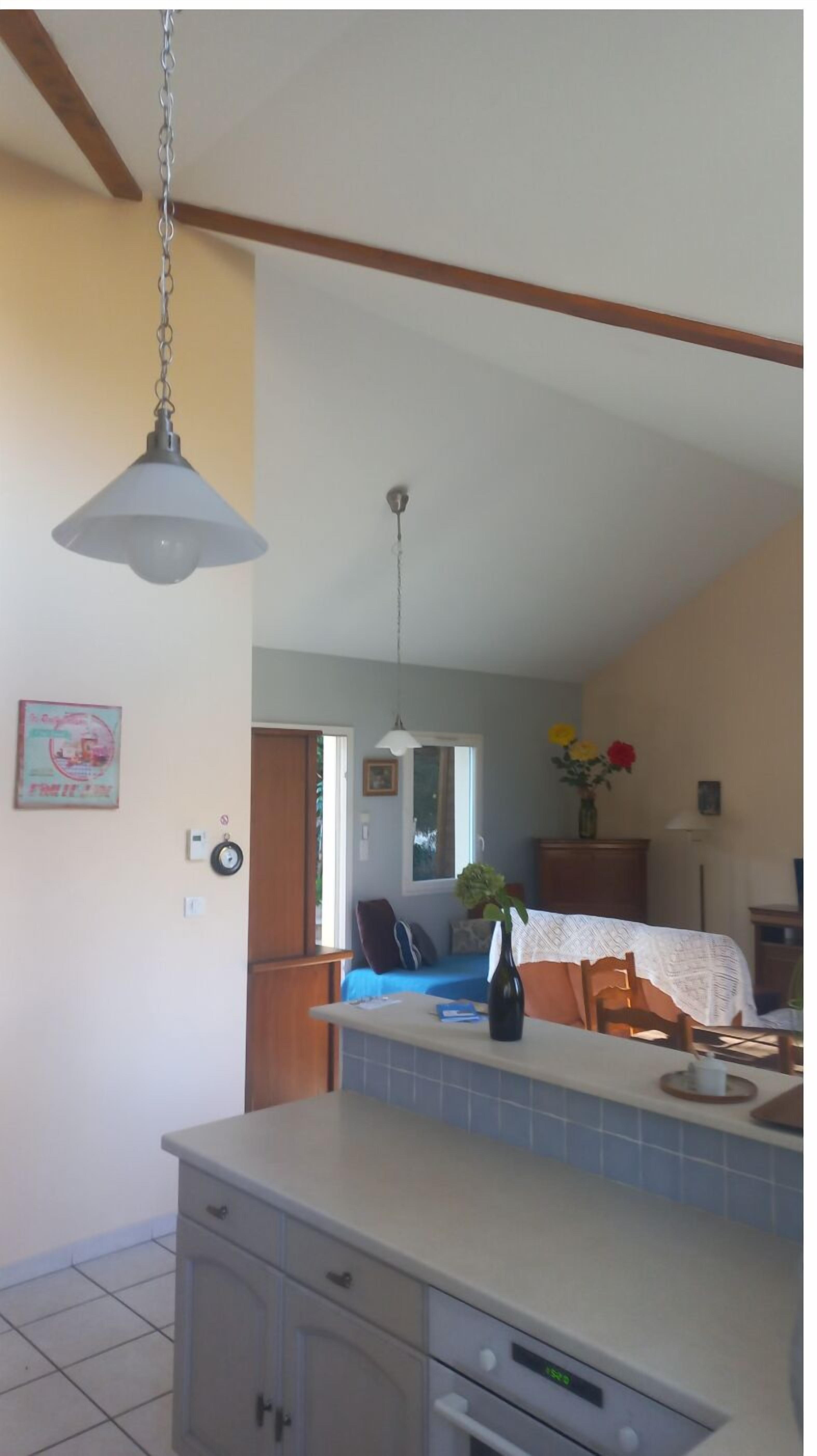 A kitchen with a central island, a dining area with a table and chairs, and a view of the living room.