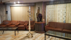 Una sala de estar con sofás de cuero marrón, una mesa de centro de vidrio y una lámpara de latón.