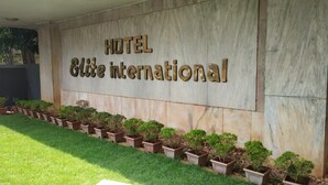 Señal de HOTEL Elite International con una fila de plantas en macetas al frente.