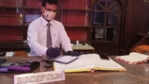 Una mesa de recepción con un cartel que dice "RECEPTION", una computadora y varios documentos.