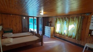 A room with two wooden beds, a white dresser, and a window with floral curtains.