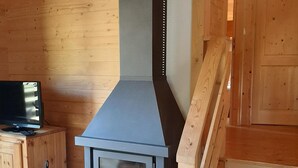 A modern kitchen with a built-in stove, wooden cabinets, and a television on a wooden stand.