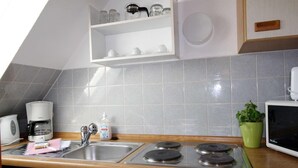 A kitchen with a Siemens coffee maker, a sink, a Juno stove, and a green potted plant. - FeWo Düneneck 14- OG (3) (St. Peter-Ording)