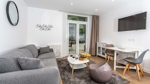 A modern living room with a grey sofa, a coffee table, and a TV mounted on the wall. - Hôtel Ty Mad (Groix)