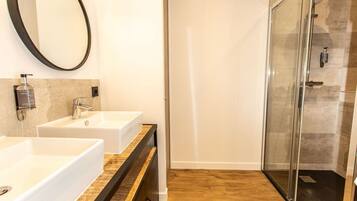 A bathroom with two white sinks, a large mirror, and a glass-enclosed shower.