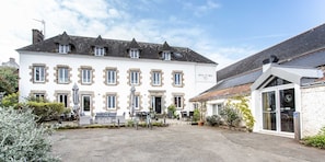 A hotel with a courtyard, outdoor seating, and a sign reading "Hôtel Ty Mad". - Hôtel Ty Mad (Groix)