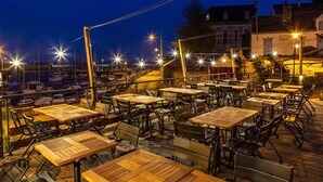 An outdoor dining area with tables and chairs, overlooking a marina with boats. - Hôtel Ty Mad (Groix)