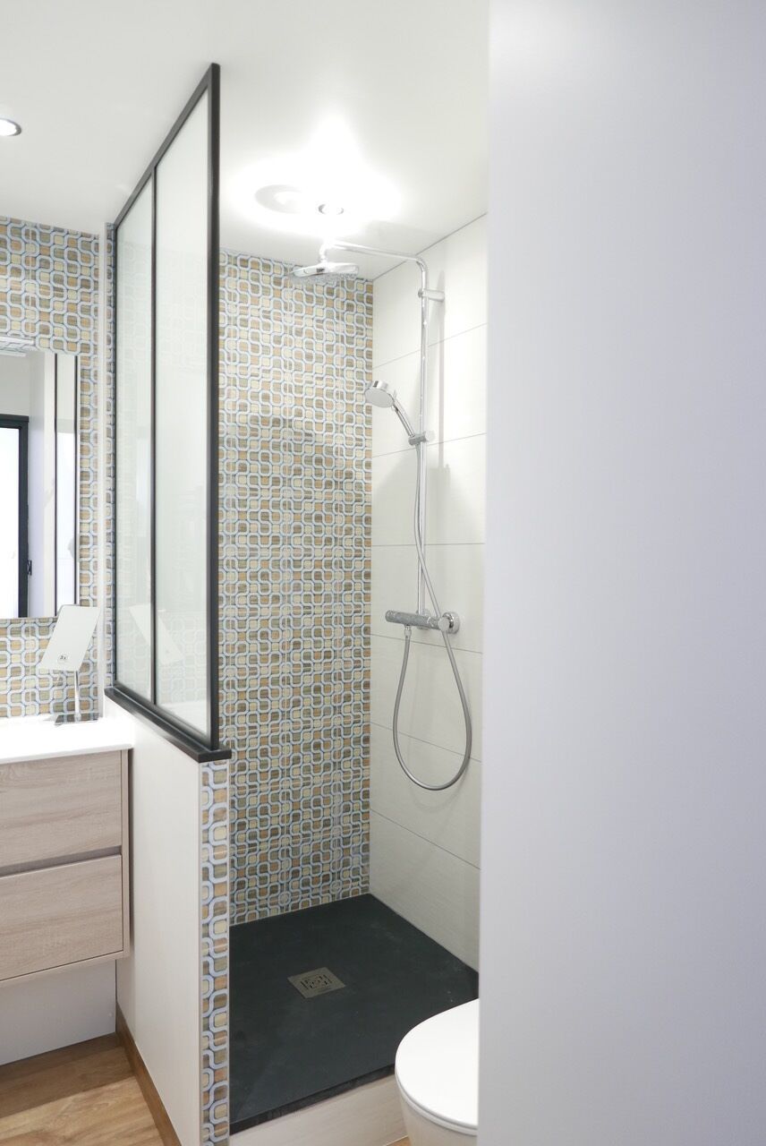A bathroom with a shower, a toilet, and a mirror.