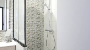 A bathroom with a shower, a toilet, and a mirror.
