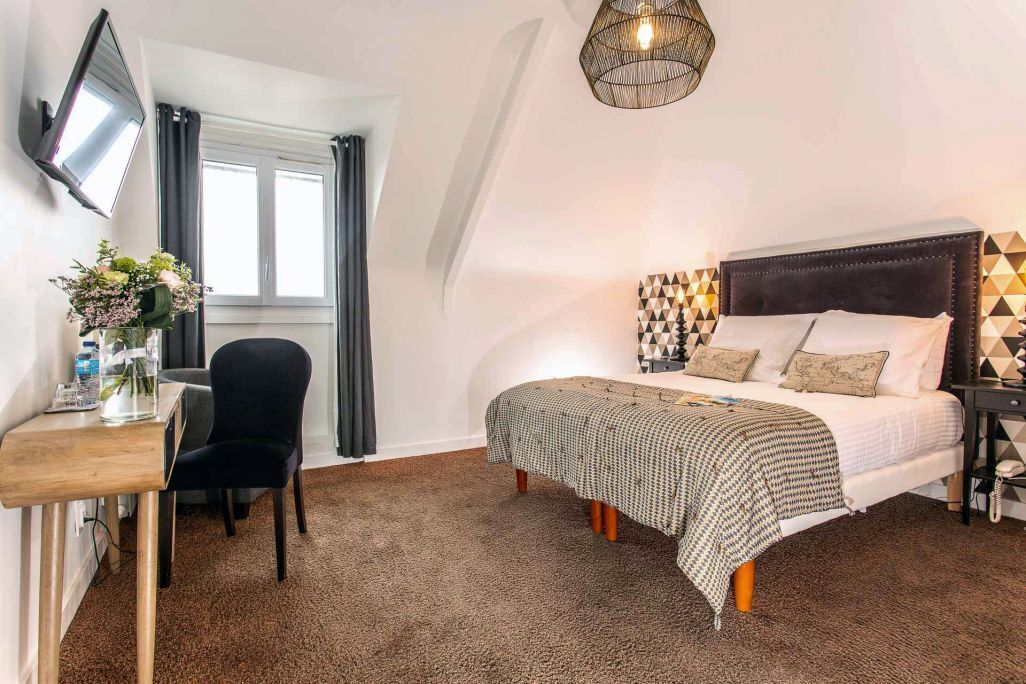 Ein Schlafzimmer mit Bett, Nachttisch, Stuhl und einem an der Wand montierten Fernseher.