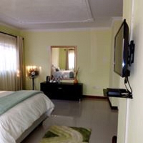 A hotel room with a bed, a dresser, a television mounted on the wall, and a mirror on the wall.
