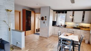 Een moderne keuken met witte kastjes, een eethoek met een houten tafel en stoelen, en een inbouwoven.