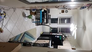Une cuisine équipée d’une table à manger, de chaises et d’une fenêtre avec des barreaux. On y trouve également un four à micro-ondes, une bouilloire et un réfrigérateur.