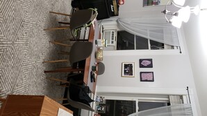 Un coin repas comprenant une table, des chaises, une lampe et des tableaux encadrés accrochés au mur.
