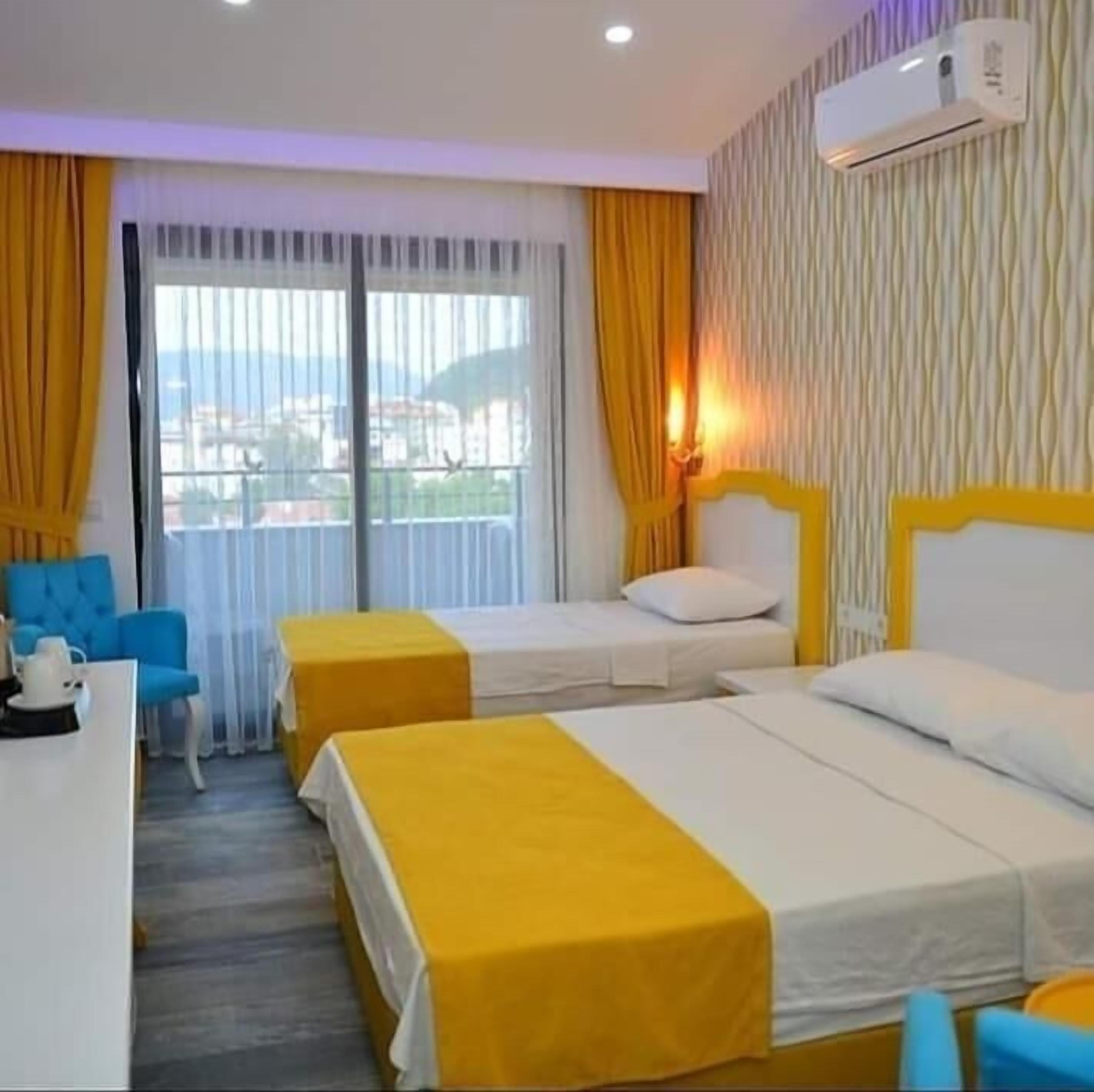 Una habitación de hotel con dos camas, un escritorio, una silla y una ventana con cortinas.