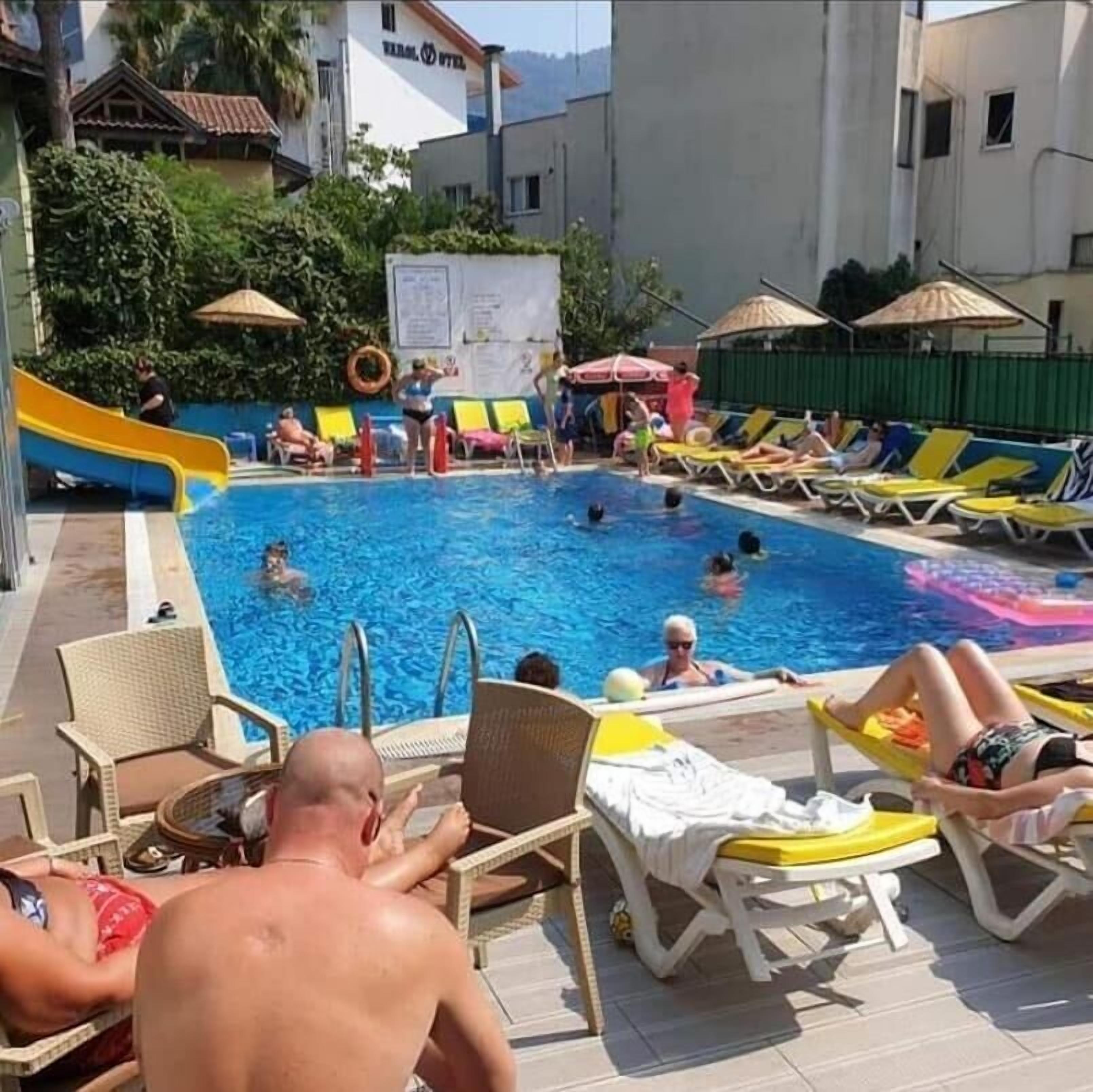 A swimming pool with lounge chairs and a slide.