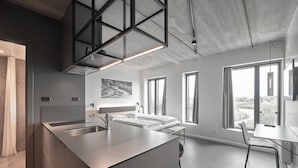 A modern, minimalist bedroom with a large window, a bed, and a desk.