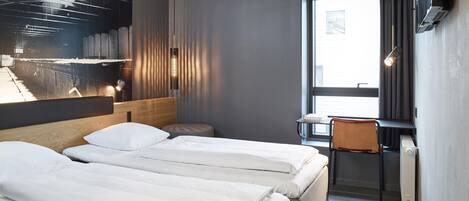A modern hotel room with two beds, a desk, and a large window.