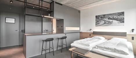 Una habitación de hotel moderna con cama, escritorio y zona de bar.
