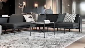 A modern living room with a sectional sofa, a round coffee table, and a patterned rug.
