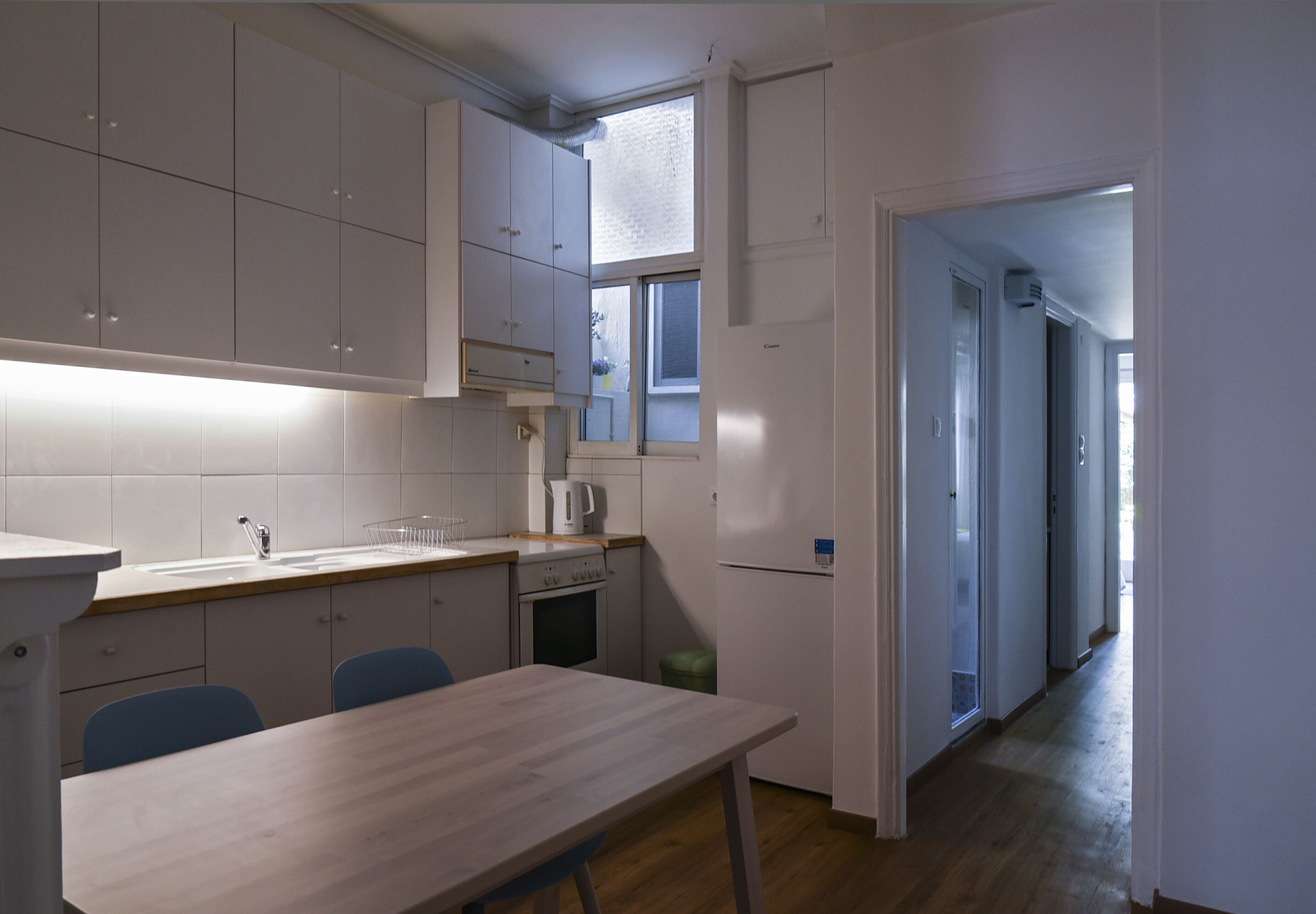 A compact kitchen with white cabinets, a wooden countertop, and a dining table with chairs.