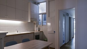 Cozinha compacta com armários brancos, bancada de madeira e mesa de jantar com cadeiras.
