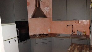 A compact kitchen with a gas stove, a sink, and a refrigerator.