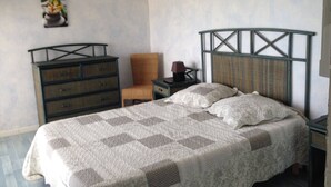 A bedroom with a bed, a dresser, a chair, and a nightstand.