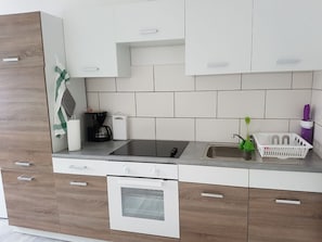 Una cocina moderna con horno integrado, cafetera y lavabo.