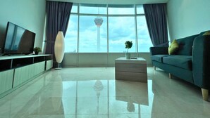 A modern living room with a large window, a television, a sofa, and a coffee table. - Yemala Suites @ Vortex KLCC (Kuala Lumpur)
