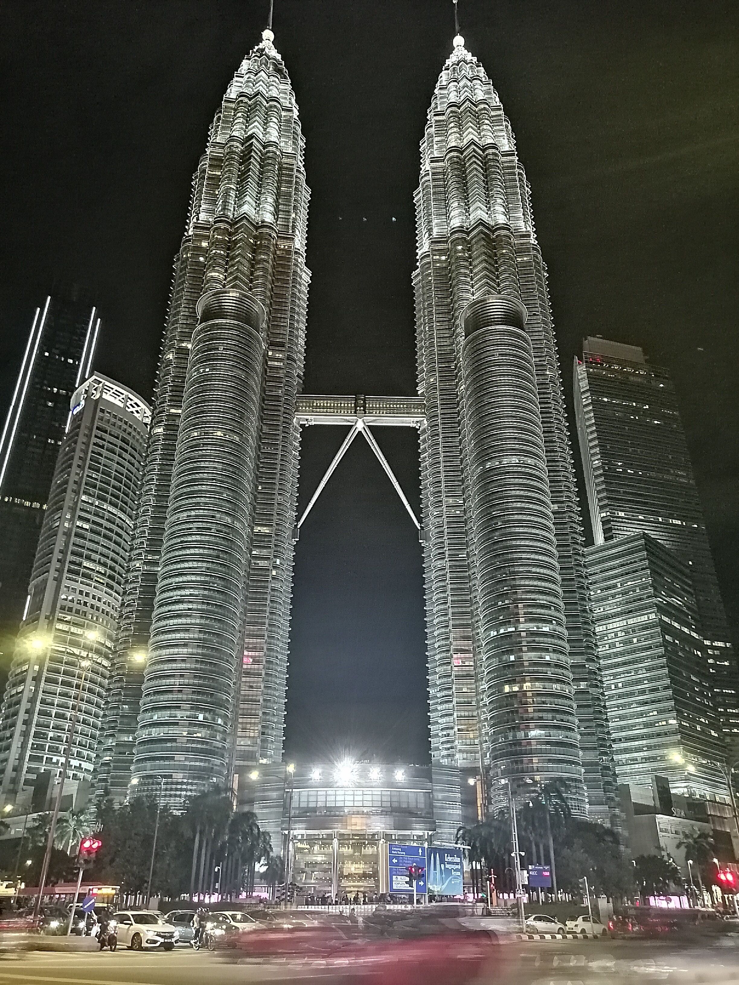 A night view of the Petronas Twin Towers with a bridge in the center.