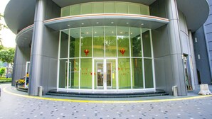 A modern building with a curved entrance, large glass windows, and a green facade. - Yemala Suites @ Vortex KLCC (Kuala Lumpur)