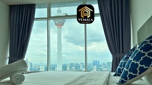 A hotel room with a bed, a view of a cityscape, and a logo for Yemala Suites. - Yemala Suites @ Vortex KLCC (Kuala Lumpur)