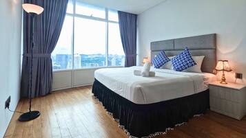 Une chambre d’hôtel avec un grand lit, une table de chevet, une lampe et une vue sur la ville par une grande fenêtre.